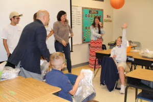Brian Kish, president of the Emeril Lagasse Foundation, prepares to toss a bag of new uniforms to Southside Elementary student Karoline Norris, after giving uniforms to classmate Gavin Davis. Looking on, from left to right, are Southside Elementary classmate Mandeville students Chase Erickson and Katherine Treuting, and KINDD Founder Karen Treuting.